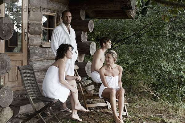 Vier Personen entspannen sich außerhalb der Sauna in einem Wellnessbereich.