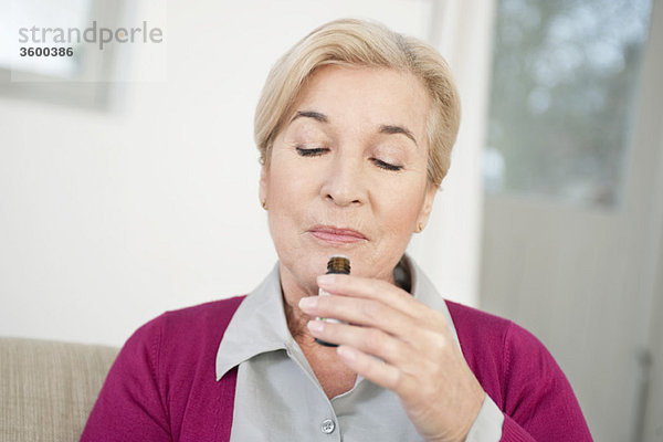 Nahaufnahme einer Frau,  die Aromatherapieöl riecht
