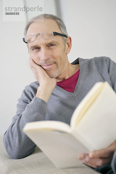 Porträt eines Mannes,  der ein Buch hält und lächelt