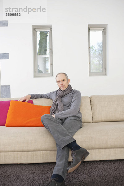 Porträt eines Mannes,  der auf einer Couch sitzt