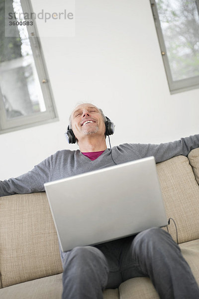 Mann mit einem Laptop und Musik hören