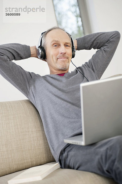 Mann mit einem Laptop und Musik hören