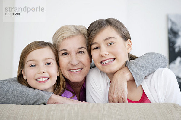 Porträt einer Frau,  die mit ihren Enkelinnen lächelt