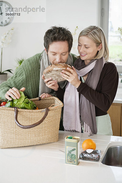 Mann riecht einen Laib Brot,  seine Frau steht neben ihm.