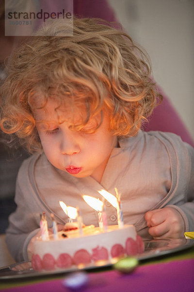 Junge,  der Kerzen auf seinem Geburtstagskuchen ausbläst.