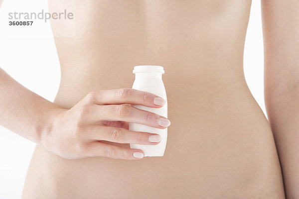 Mittelteilansicht einer Frau,  die eine Flasche probiotisches Getränk in der Hand hält.
