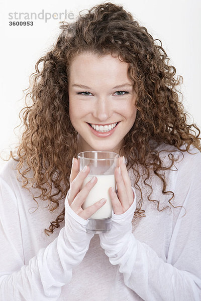 Porträt einer Frau,  die ein Glas Milch hält und lächelt
