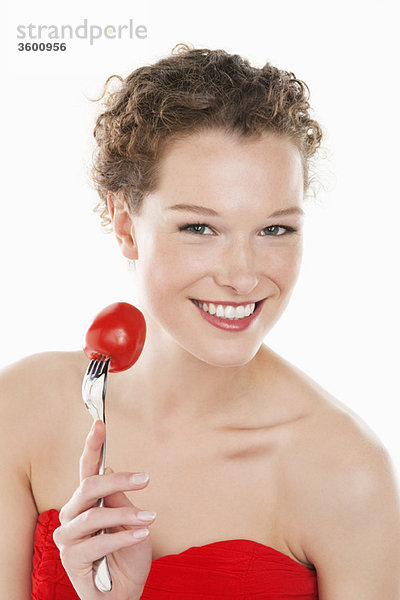 Porträt einer Frau mit einer Tomate auf einer Gabel