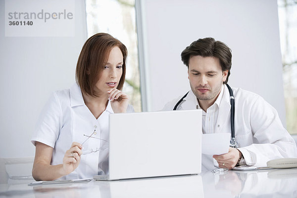 Ärzte,  die an einem Laptop arbeiten