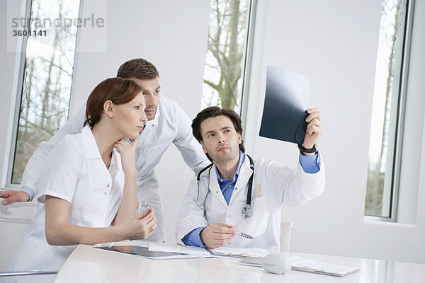 Drei Ärzte untersuchen einen Röntgenbericht