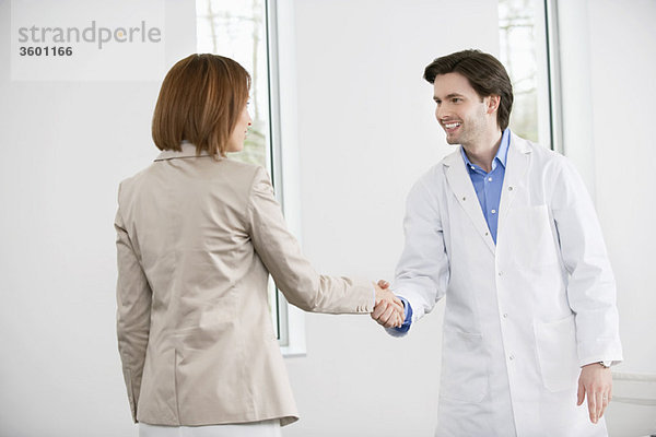 Arzt schüttelt die Hand mit einer Frau