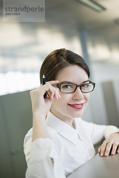 Porträt einer Geschäftsfrau,  die ihre Brille anpasst und lächelt