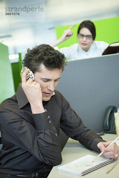 Geschäftsleute sprechen auf dem Handy,  während sein Kollege wütend aussieht.
