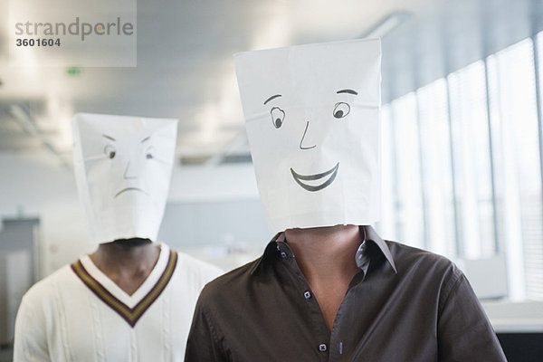 Zwei Geschäftsleute,  die Papiertüten mit fröhlichen und traurigen Gesichtern tragen.