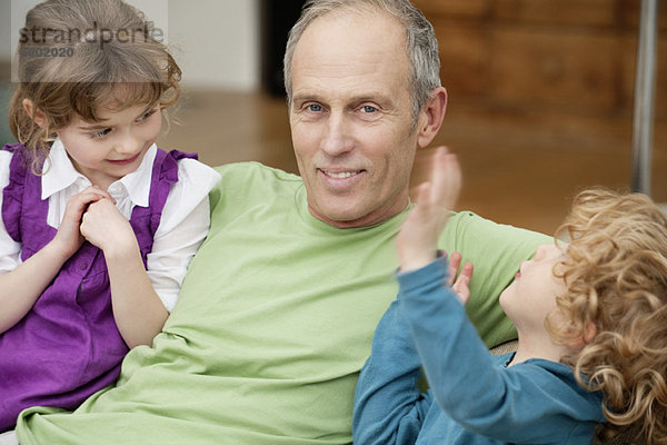 Mann sitzend mit seinen Enkeln