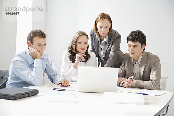 Geschäftsleute betrachten einen Laptop in einem Vorstandszimmer