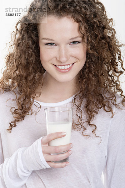 Porträt einer Frau,  die ein Glas Milch hält und lächelt