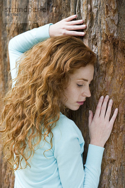 Junge Frau berührt Baum,  Portrait