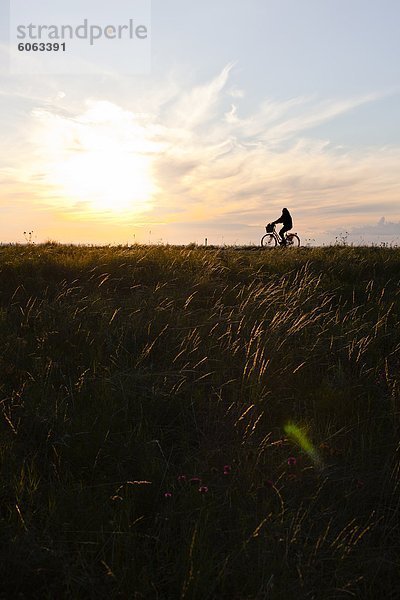 Ein Mann,  mit dem Fahrrad bei Sonnenuntergang