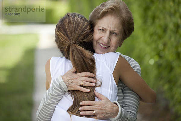 Eine ältere Frau,  die eine junge Frau umarmt.