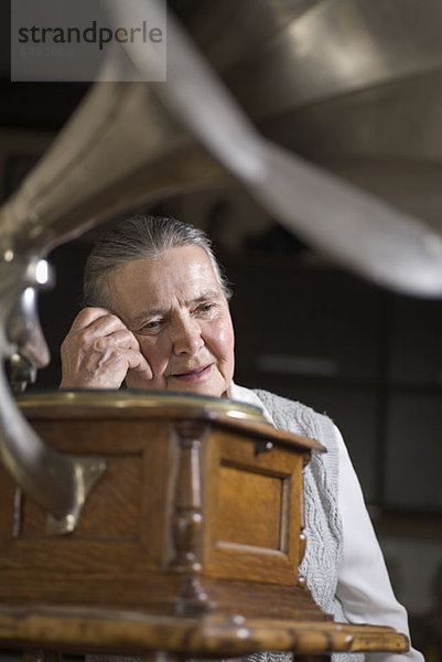 Eine ältere Frau,  die ein Grammophon hört.