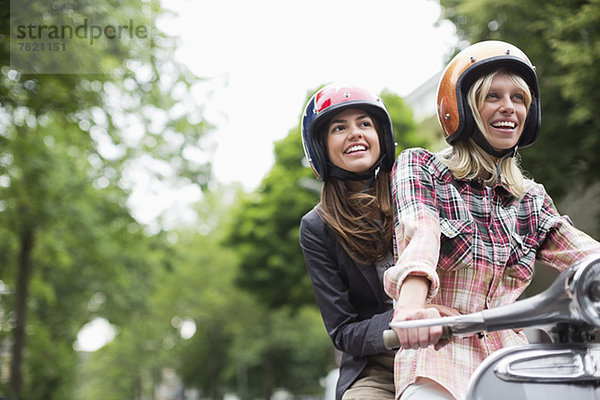 Frauen fahren gemeinsam auf dem Roller im Freien