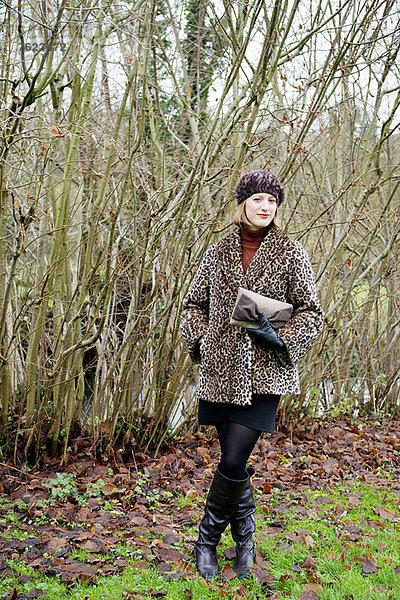 Lächelnde Frau im Wald stehend
