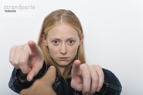 Junge Frau,  die mit den Fingern auf eine Person im Vordergrund zeigt.