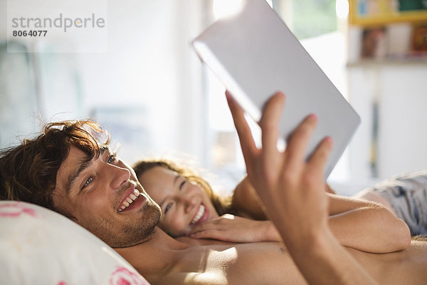 Paar mit Tablet-Computer im Bett