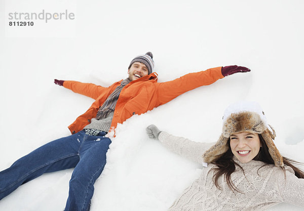 Porträt des glücklichen Paares,  das Schnee-Engel macht
