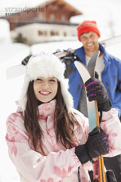 Porträt eines lächelnden Paares mit Skiern in der Außenkabine