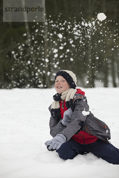 Porträt eines glücklichen Jungen,  der die Schneeballschlacht genießt.