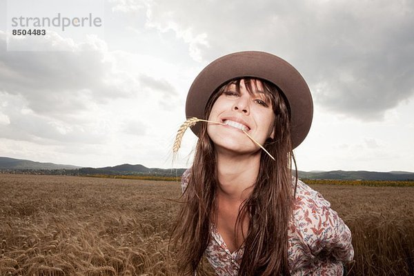 Mittlere erwachsene Frau mit Weizen im Mund