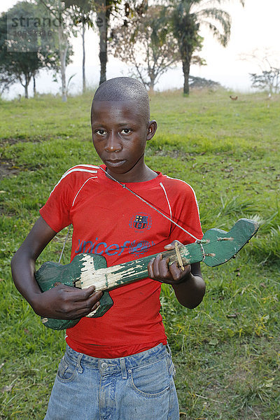 Junge spielt,  musiziert auf selbst gebauter Gitarre,  Matamba-Solo,  Provinz Bandundu,  Republik Kongo