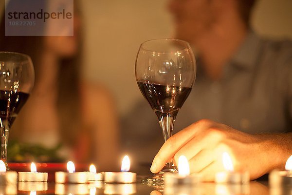 Paar genießt ein Glas Rotwein bei Kerzenschein