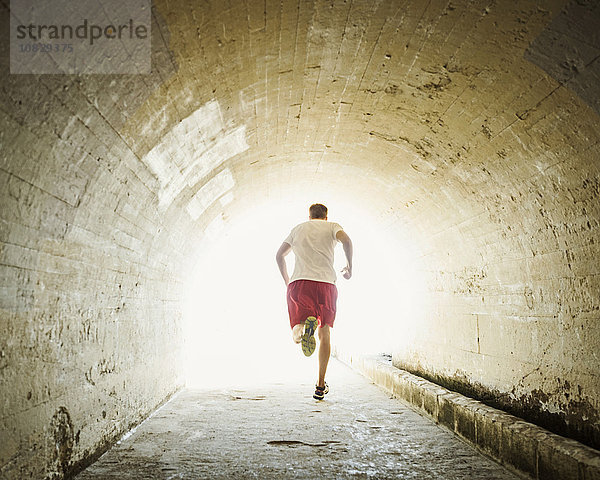 Kaukasischer Mann joggt im Tunnel