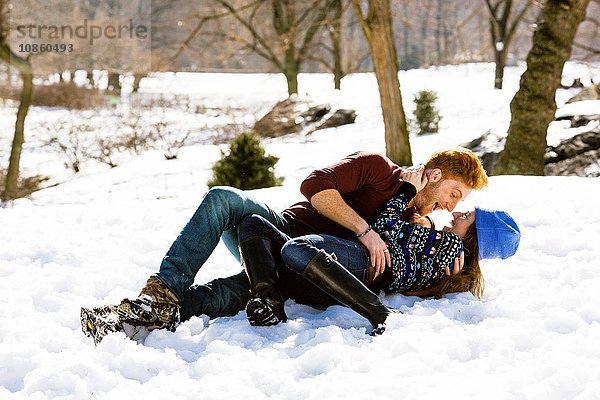 Romantisches junges Paar im verschneiten Central Park liegend,  New York,  USA