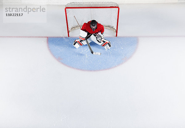 Hockeytorwart in roter Uniform zum Schutz des Tornetzes