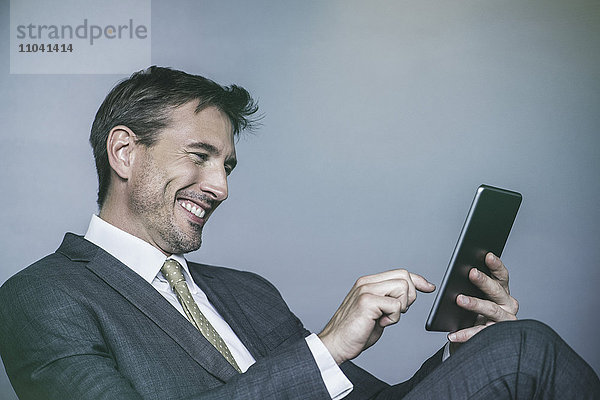 Der Mann lacht,  während er ein digitales Tablett benutzt.