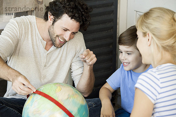 Familie mit einem Kind schaut gemeinsam auf die Weltkugel