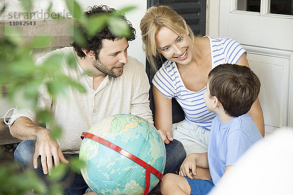 Familie mit einem Kind schaut gemeinsam auf die Weltkugel