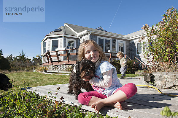 Kleines Mädchen sitzend an Deck mit Haushund