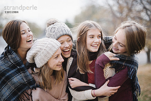 Fünf junge Leute,  Mädchen,  Freunde in warmen Schals und Wollmützen im Freien.