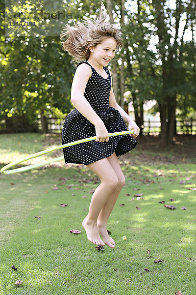 Lächelndes Mädchen spielt mit Plastikreifen auf einem Feld