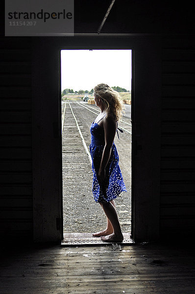Frau steht in der Tür eines Zuges im Rangierbahnhof