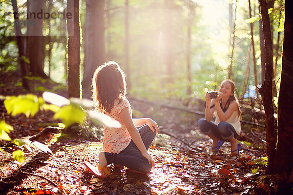 Kaukasisches Mädchen fotografiert Schwester im Wald