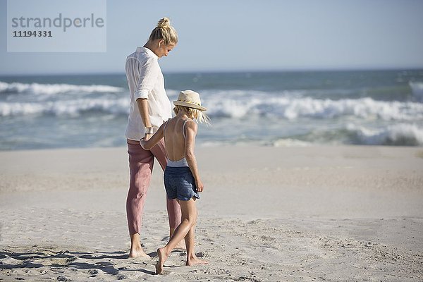 Profil einer Frau mit ihrer Tochter,  die am Strand spazieren geht