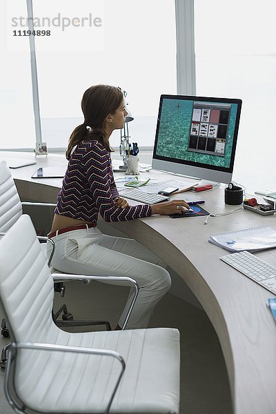 Profil einer Geschäftsfrau,  die auf einem Desktop-PC im Büro arbeitet