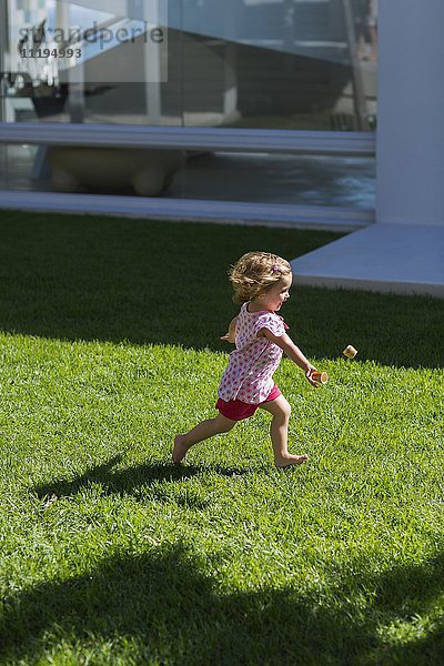 Profil eines kleinen Mädchens,  das auf Rasen spielt