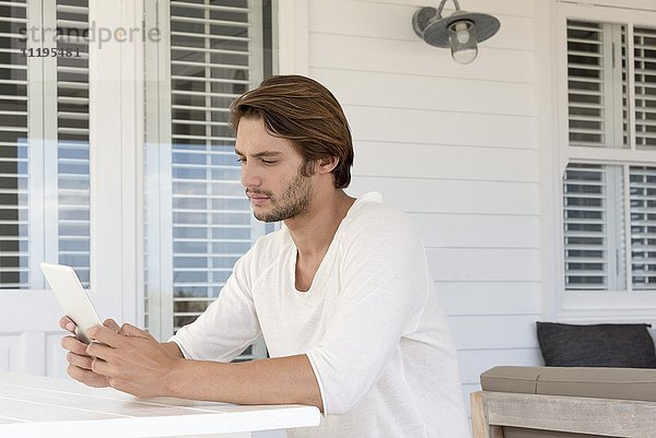 Junger Mann mit einem digitalen Tablett zu Hause